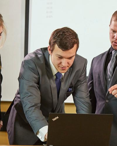 Students gather around a laptop for a presentation