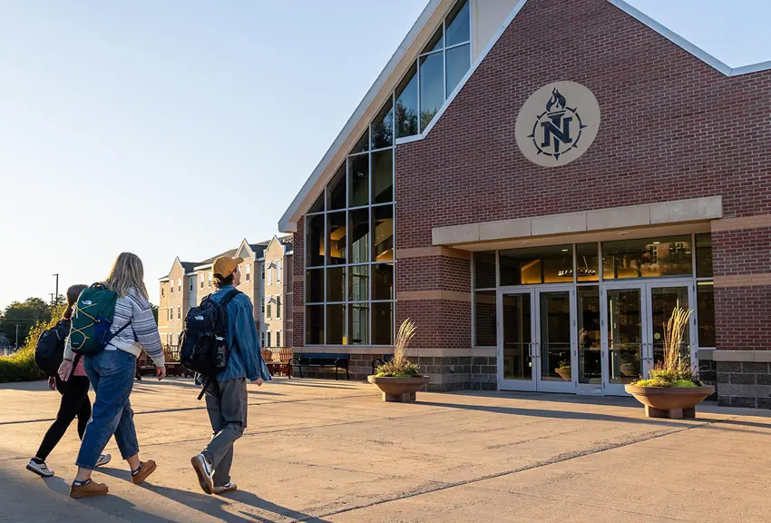 Three NMU students walking from class into The Woods residence hall.