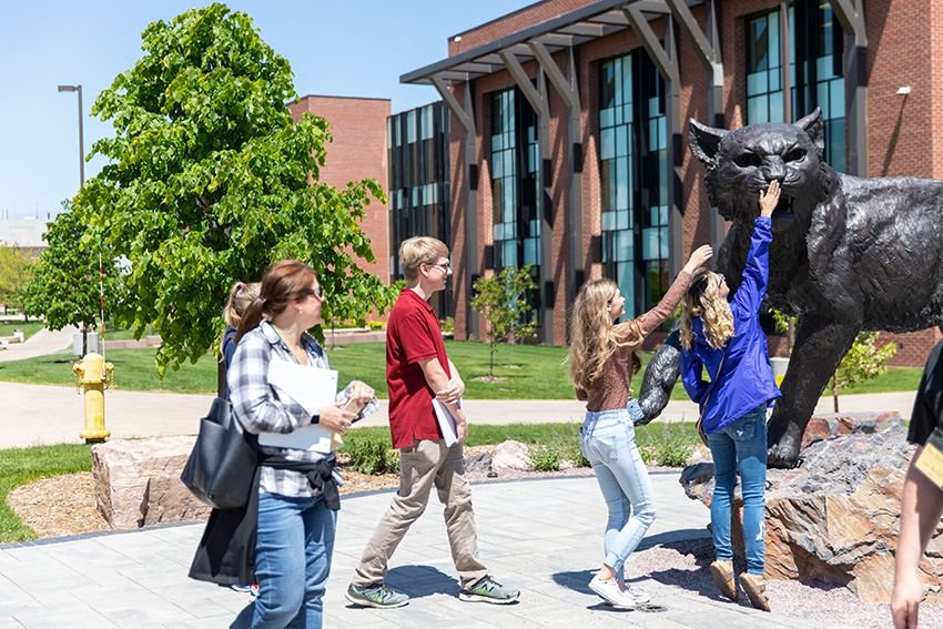 A group of future NMU students visiting the NMU Wildcat statue outside Jamrich Hall.